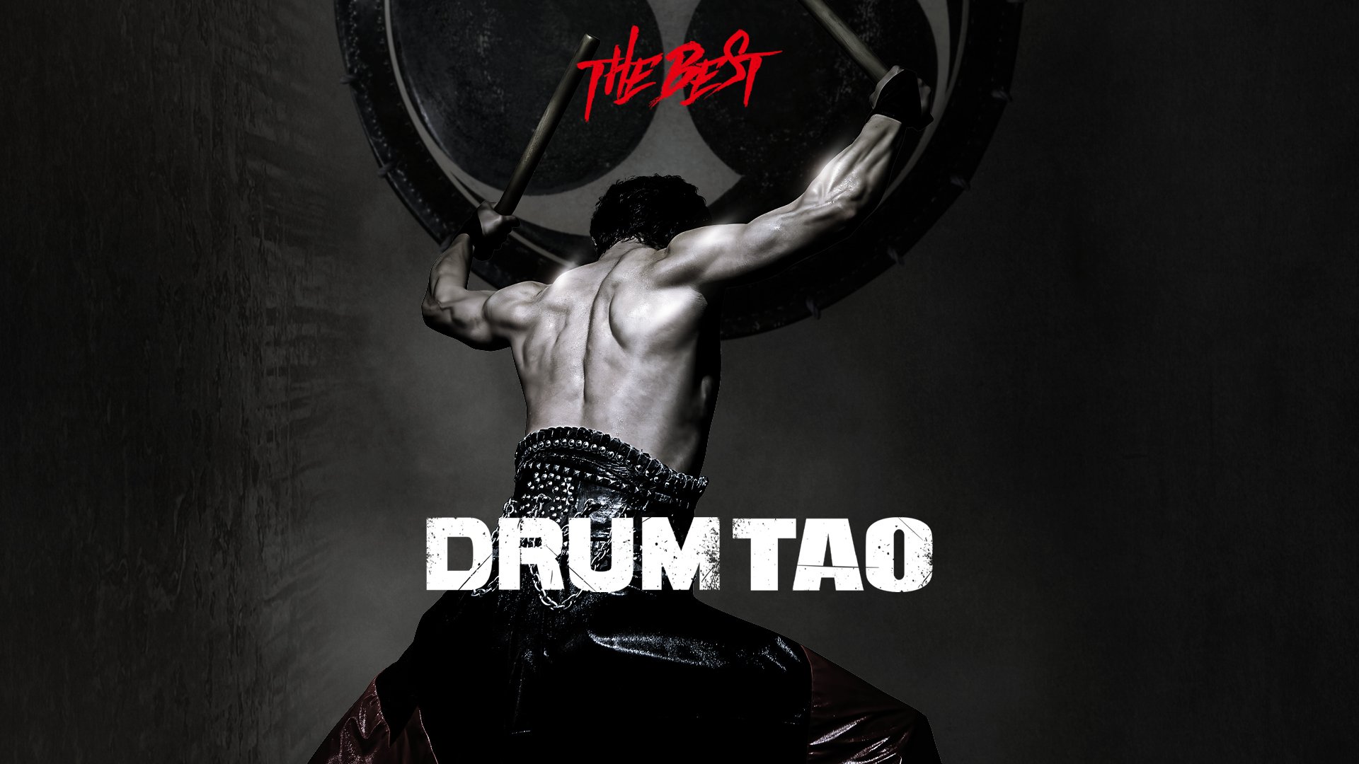 Werbeplakat für „The Best Drum Tao“. Im Zentrum steht eine Person mit freiem Oberkörper, die mit erhobenen Armen zwei Trommelschlägel hält und vor einer großen japanischen Trommel positioniert ist. Das Bild ist überwiegend in dunklen Schwarz- und Grautönen gehalten und setzt die muskulöse Rückenansicht der Person kontrastreich in Szene. Über der Trommel steht in roter Schrift „The Best“, darunter der Titel „DRUM TAO“ in großen weißen Buchstaben. Die Aufnahme vermittelt die Kraft und Dynamik einer Taiko-Trommelperformance.