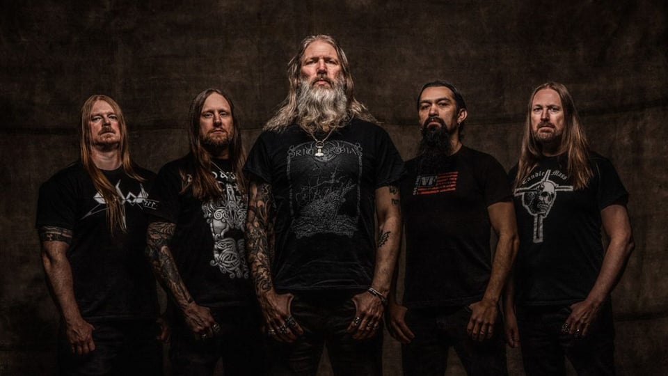 Foto für die Veranstaltung ‚AMON AMARTH – THE ALLFATHER AWAKENS: EUROPE & UK 2026‘ mit der Band vor einem dunklen Hintergrund