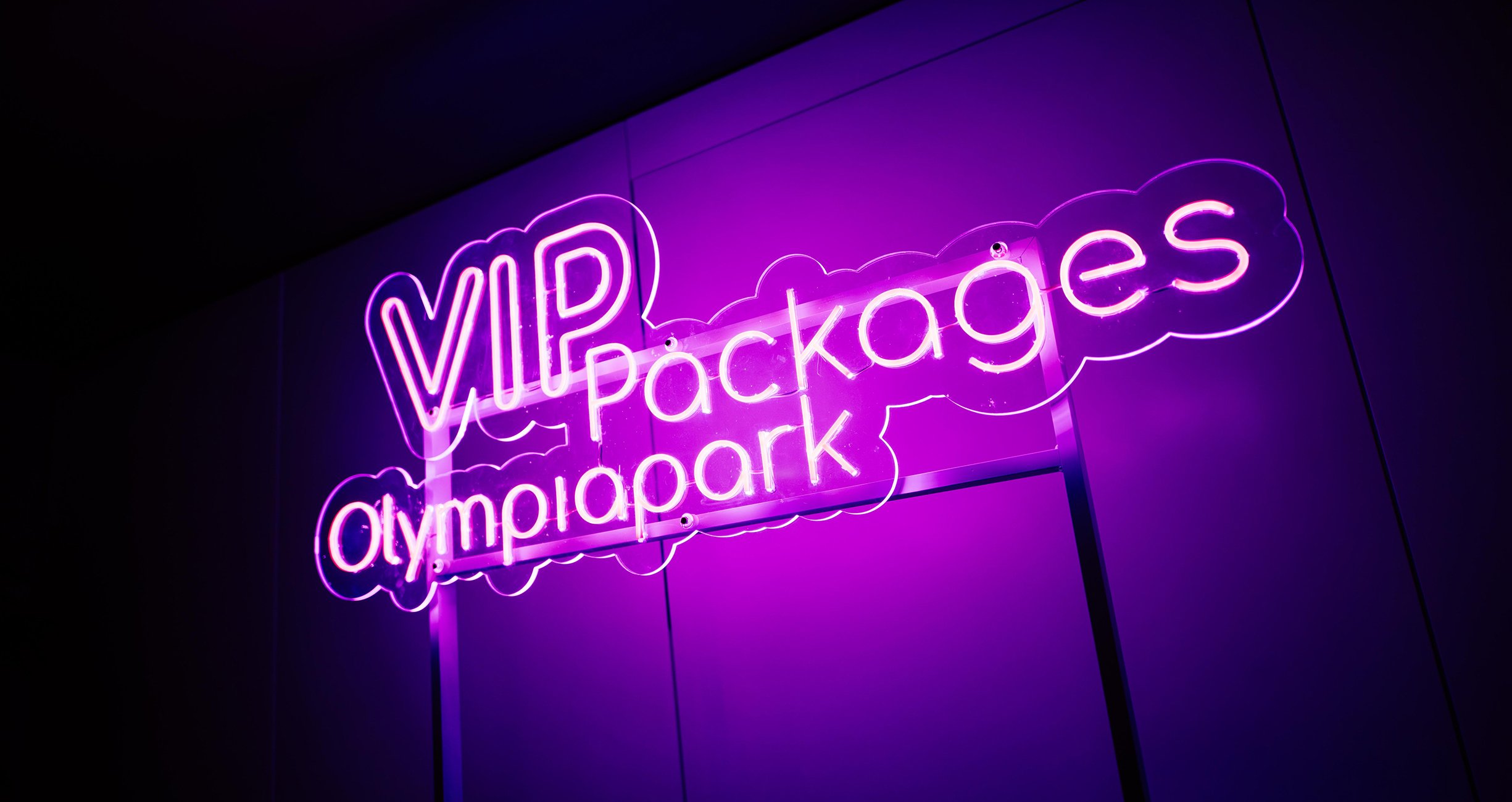 Foto von einem lilanem Neonschild mit der Aufschrift "VIP Packages Olympiapark"