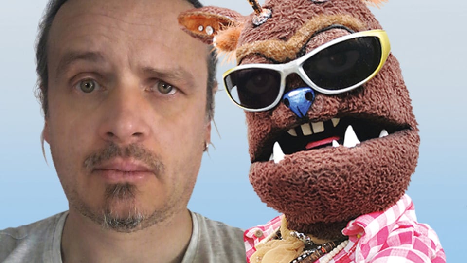 Porträt einer Person neben einer Handpuppe mit Sonnenbrille vor blauem Hintergrund, Pressebild für ein Kabarett- oder Comedyprogramm mit Figurenspiel.