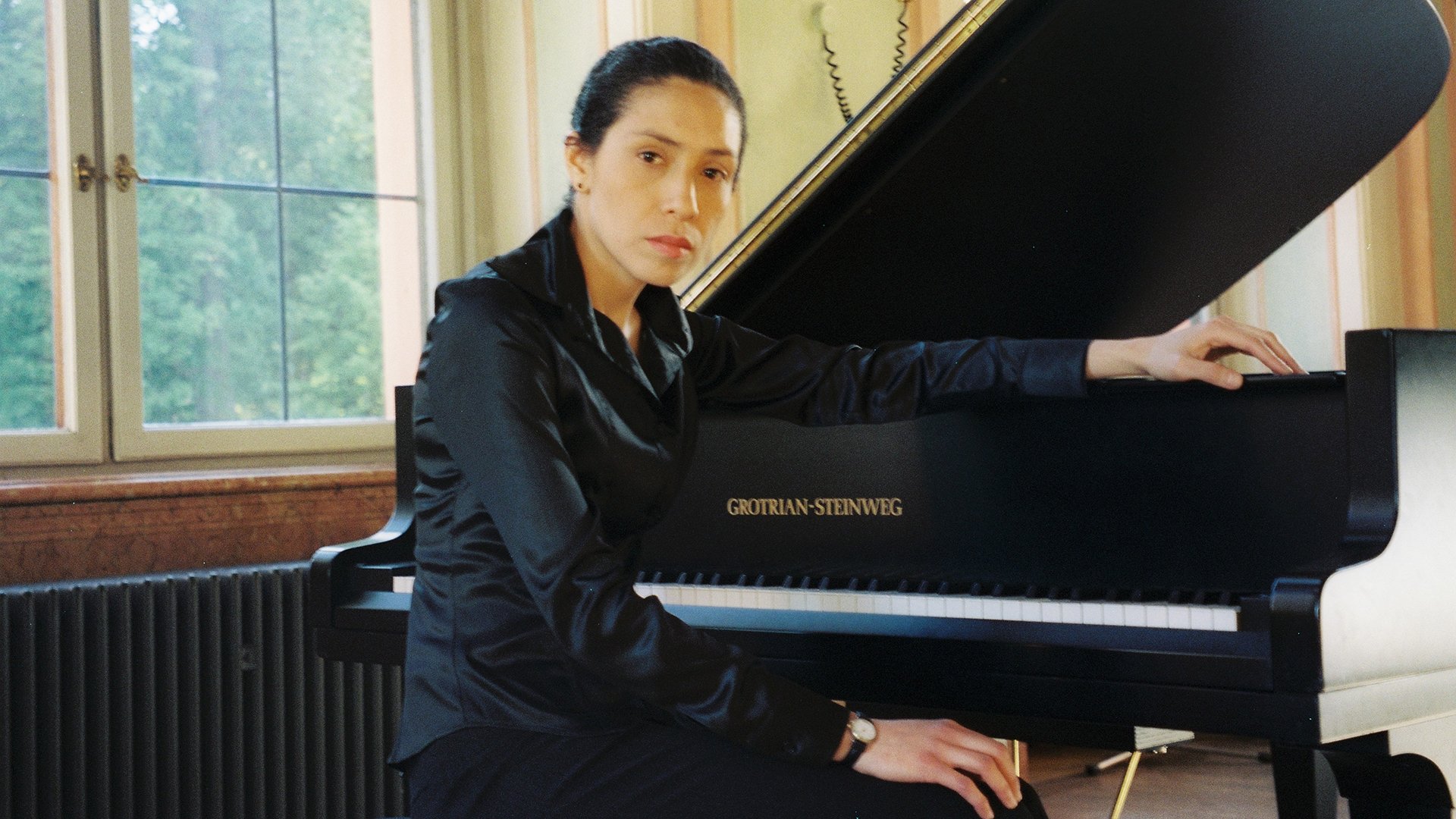 Die Künstlerin in schwarzer Kleidung am Konzertflügel sitzend