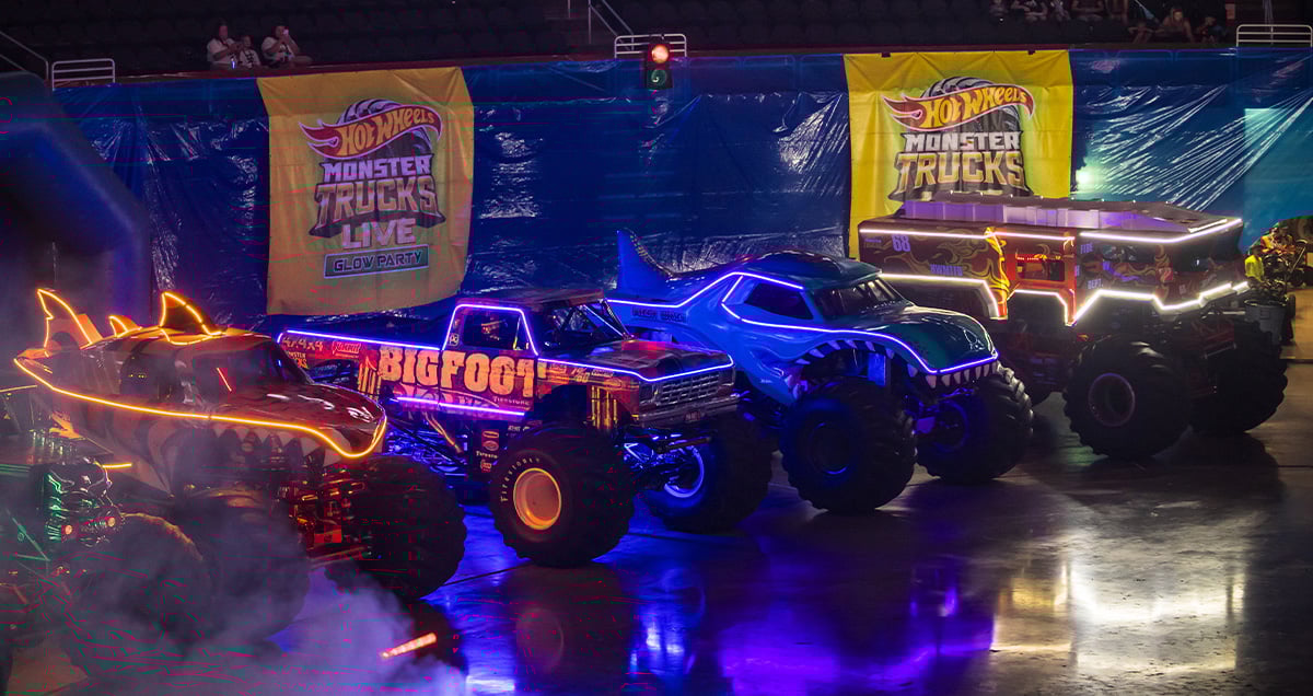 Vier Monstertrucks vor dunklem Hintergrund