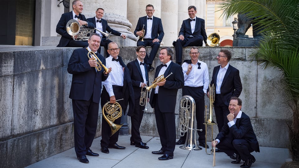 Das Orchester mit Instrumenten in einem Hof vor einer Mauer