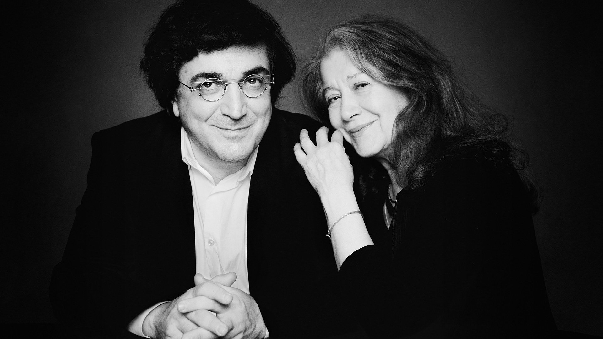 Schwarzweiß-Pressefoto von Martha Argerich und Sergei Babayan, Porträt der beiden Pianisten vor dunklem Hintergrund.