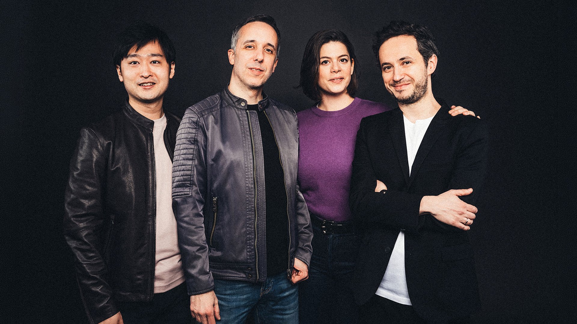 Quatuor Ébène mit vier Musiker:innen in dunkler Kleidung vor schwarzem Hintergrund, nah nebeneinander stehend in einer Studioaufnahme, ohne Instrumente im Bild sichtbar.