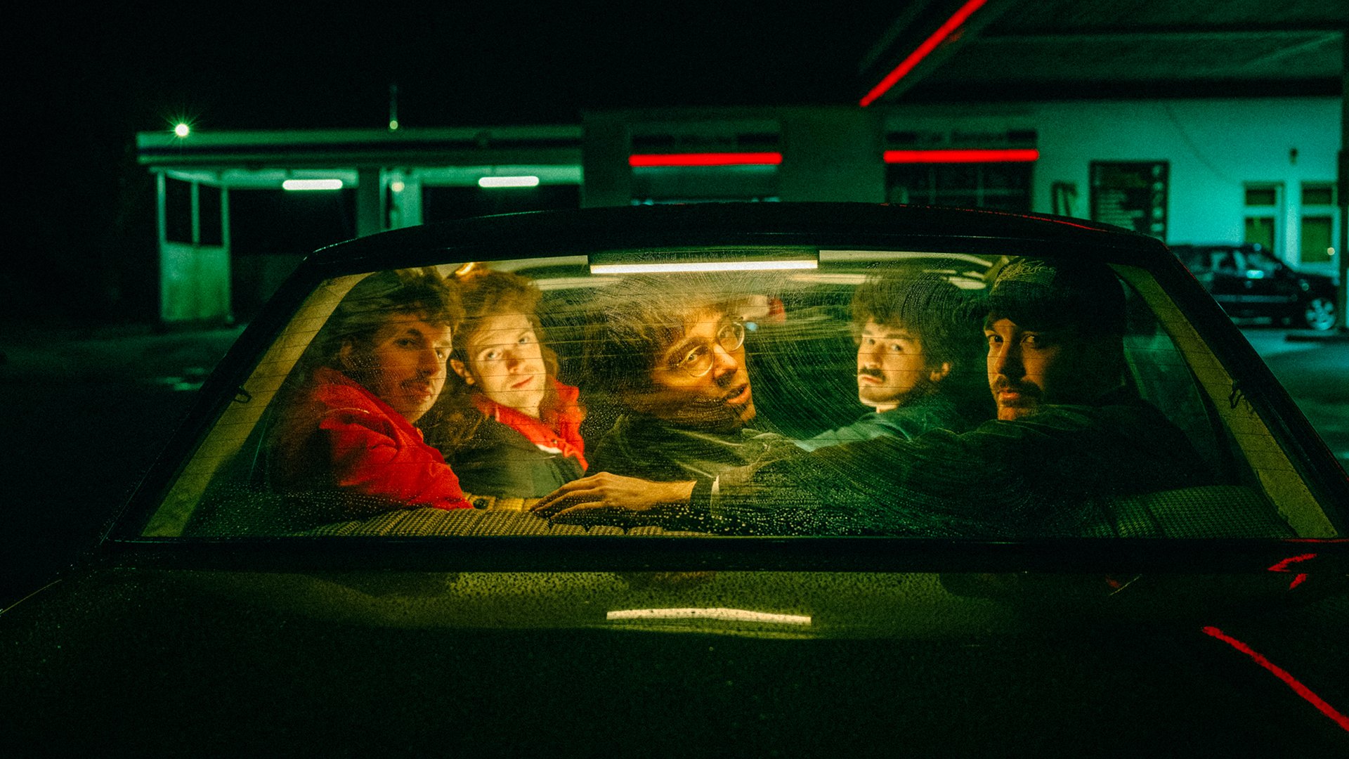 Fünf Personen blicken aus dem Inneren eines Autos durch die Heckscheibe