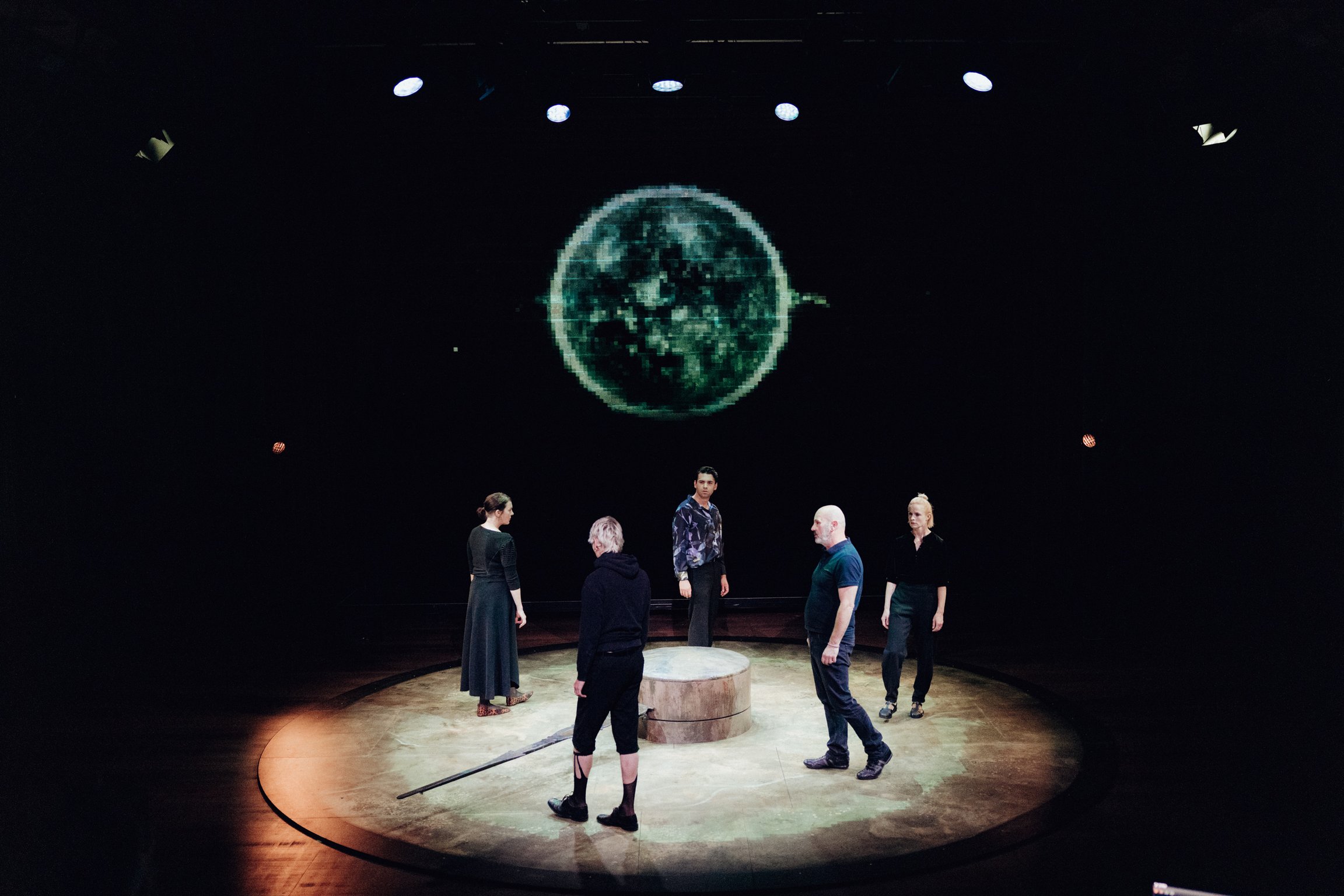 Fünf Darsteller auf einer runden Bühne gehen im Kreis