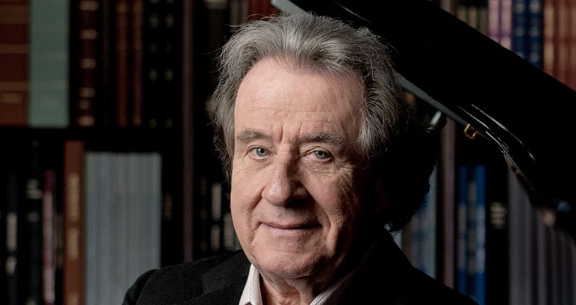 Rudolf Buchbinder vor einem Bücherregal