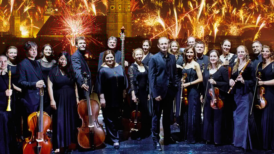 Foto für das Event Feuerwerksmusik – mit Musiker:innen und Feuerwerk im Hintergrund.