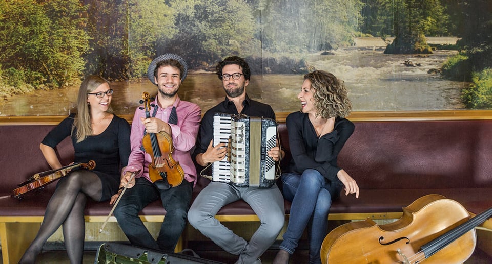 Foto der Gruppe, zwei Mädchen und zwei Jungen, die mit Instrumenten sitzen