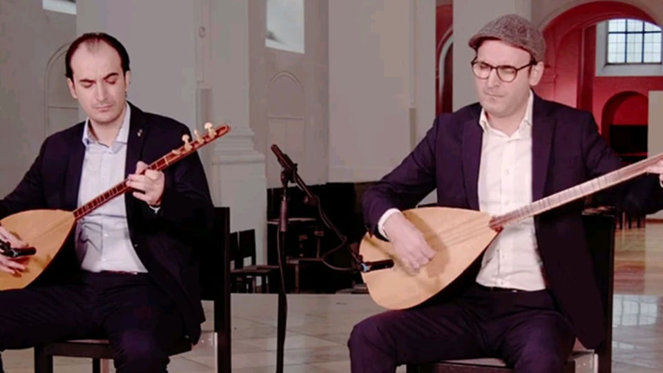 Zwei Musiker sitzen auf Stühlen mit ihren Instrumenten