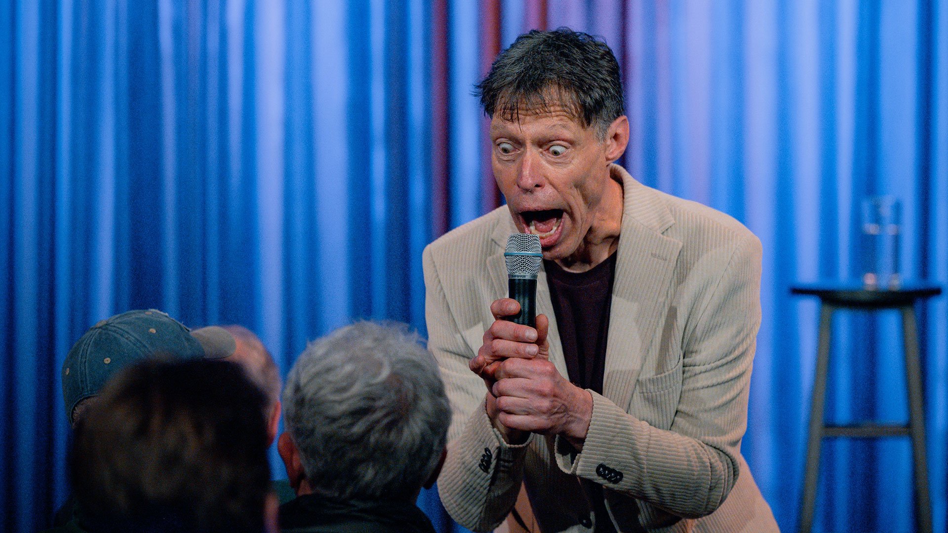 Foto des Komikers auf der Bühne mit einem Mikrofon