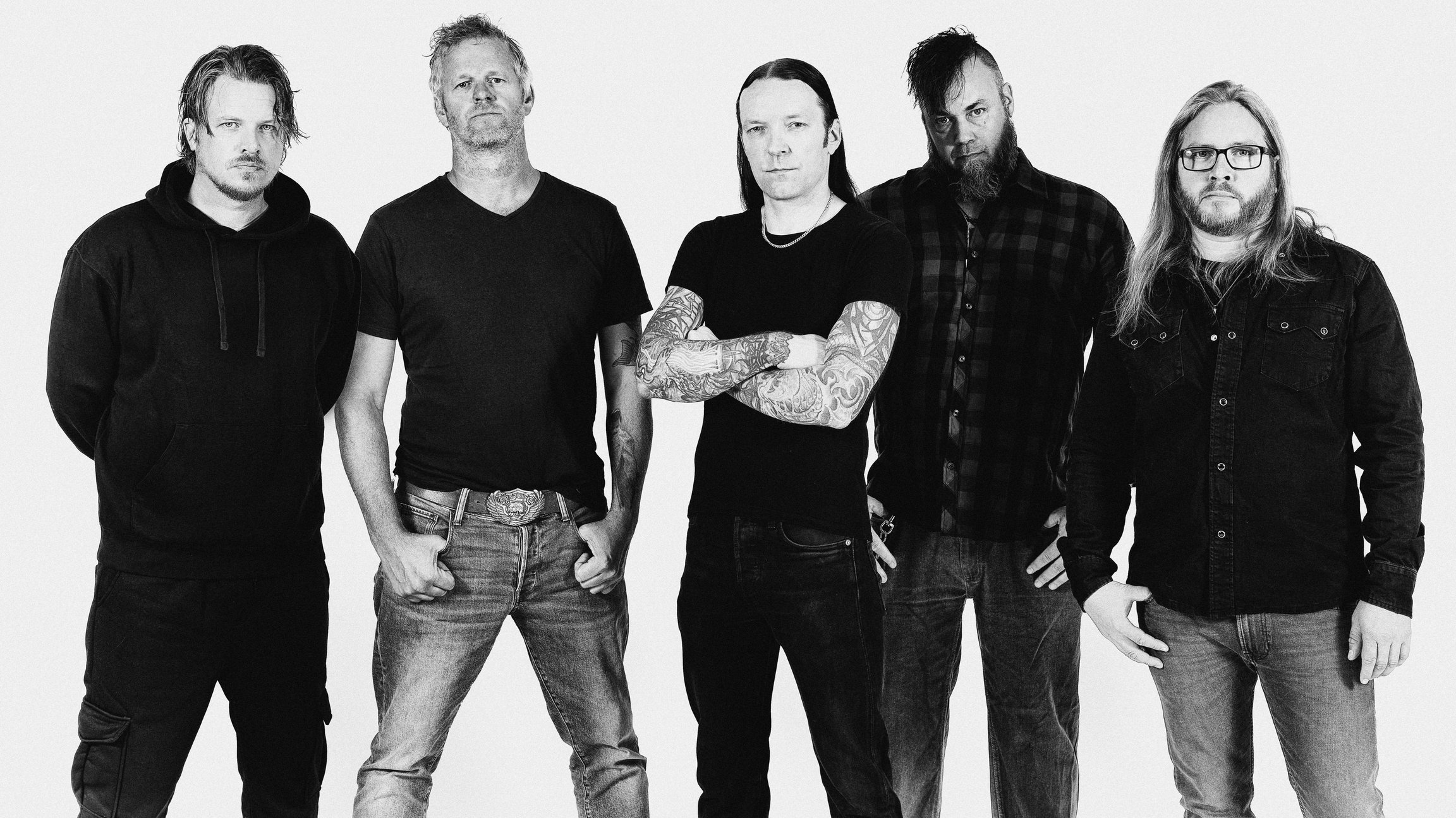 ein schwarz weiss Foto der Band tAKiDA in dunkler Freizeitkleidung vor hellem Hintergrund