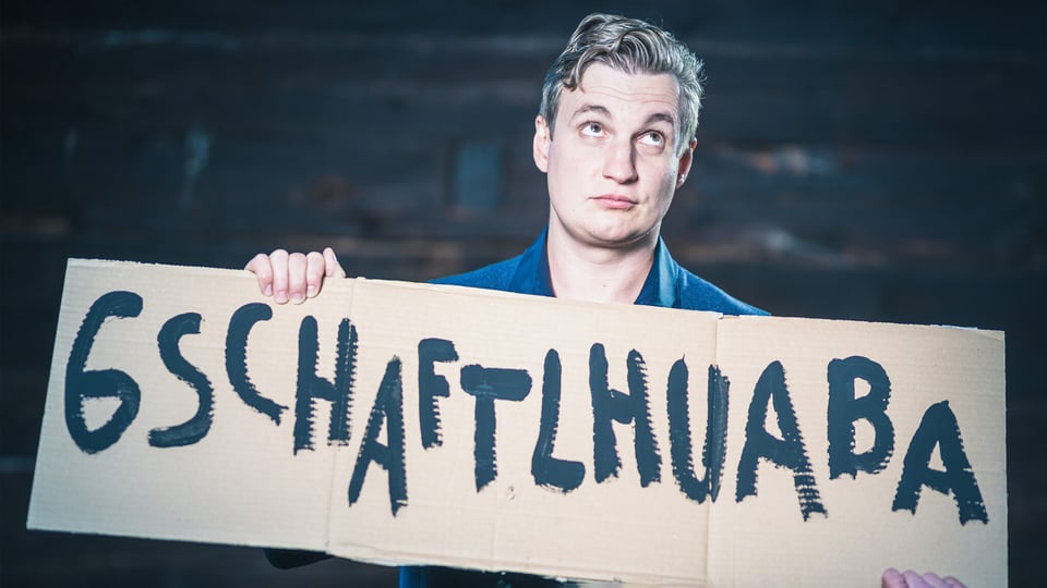 Foto für die Veranstaltung von Sebastian Huber, mit einem Karton in der Hand, auf dem etwas geschrieben steht.