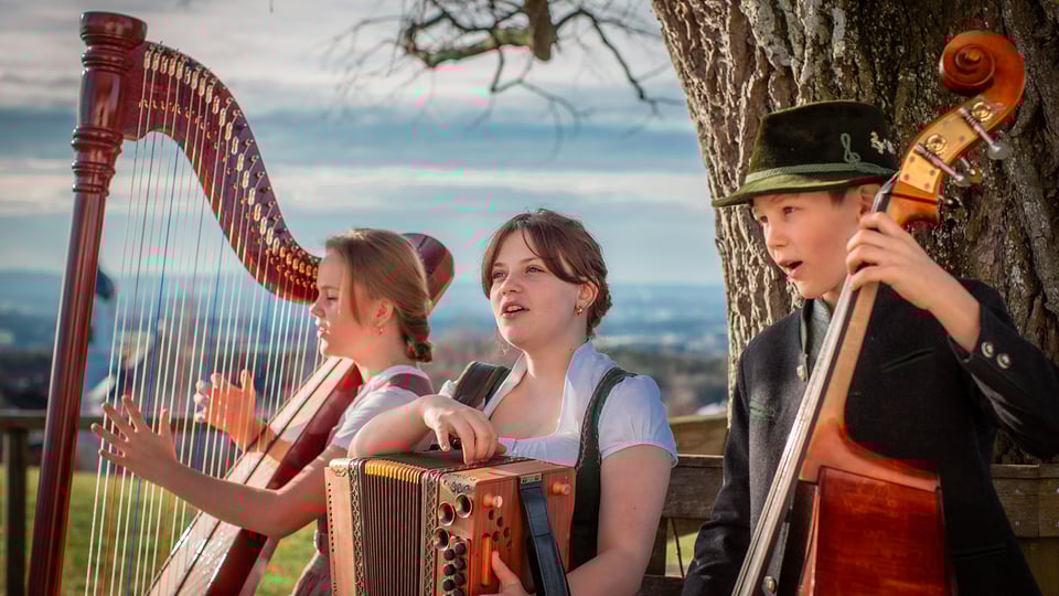 Drei Kinder mit traditionellen Instrumenten