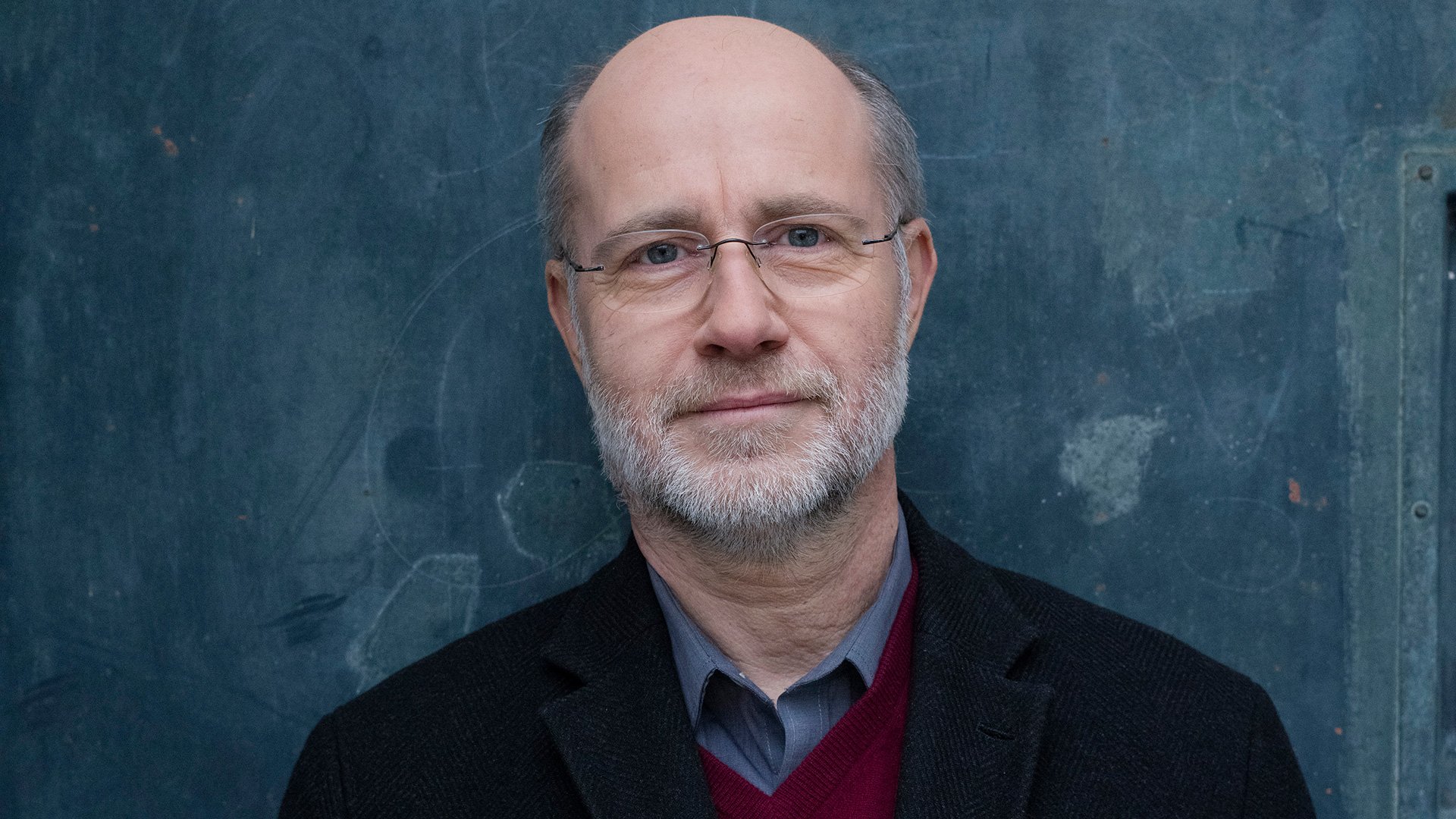 Foto für das Event von Quadro Nuevo & Harald Lesch mit einem Mann vor blauem Hintergrund.