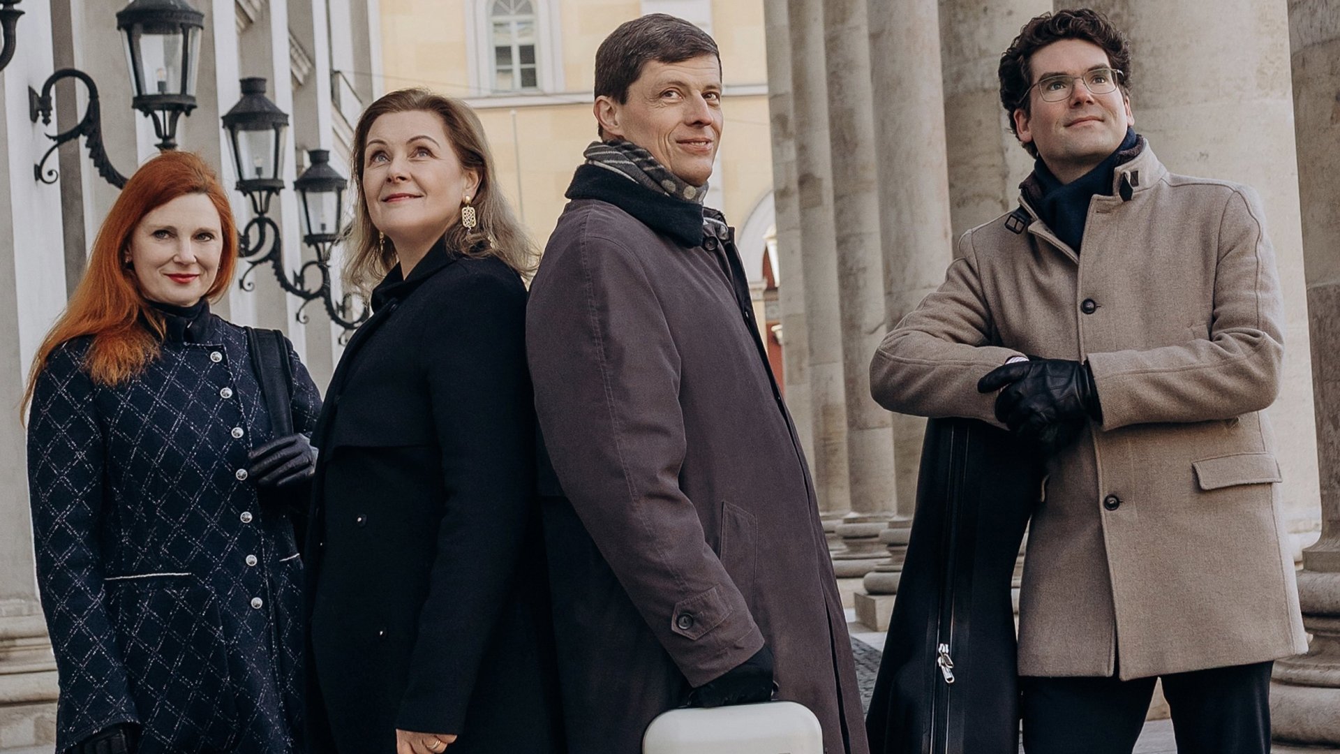 Foto für die Veranstaltung von Henschel Quartett & Hendrik Blumenroth mit den vier Mitgliedern in einer Straße zwischen Säulen und Laternen