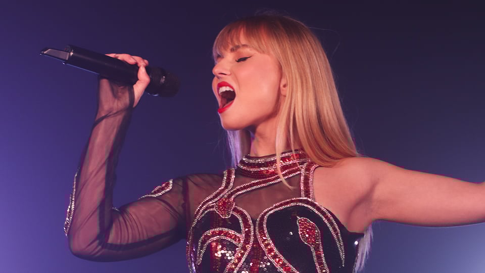 Das Plakat für das Event ONE NIGHT OF TAYLOR, mit einer jungen Frau, die ein Taylor-Swift-Tribut gibt, mit einem Mikrofon in der Hand vor blauem Hintergrund