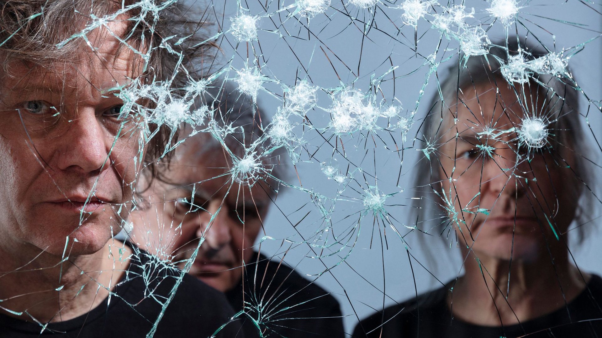 Ein Foto für die Band THE YOUNG GODS mit den drei Künstlern, die sich in einem zerbrochenen Spiegel spiegeln