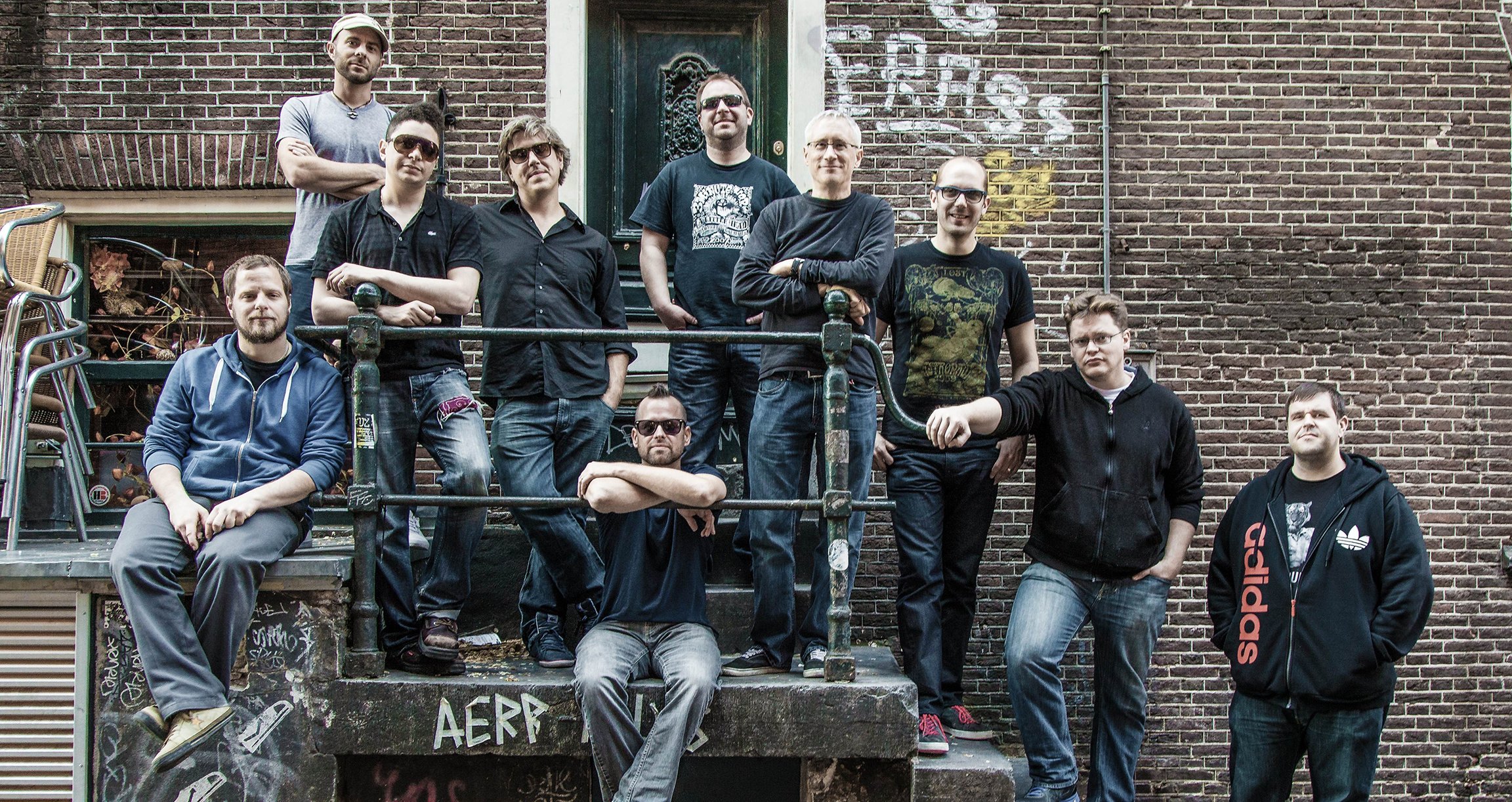 Ein Bild der Band mit Backsteinwand im Hintergrund.