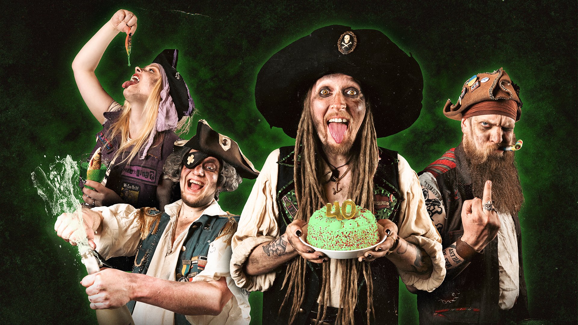 Vier Personen in Piratenkostümen vor grünem Hintergrund, eine Person hält eine Torte mit 40, andere mit Flasche und bunten Requisiten, Gruppenmotiv für Party‑Konzert