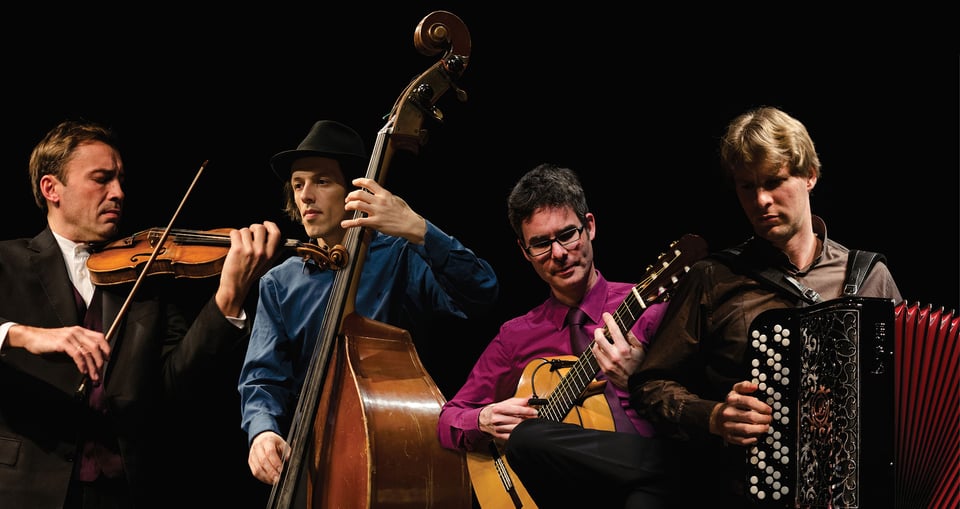 Foto der Musikgruppe ‚Gitanes Blondes‘ mit Instrumenten vor schwarzem Hintergrund