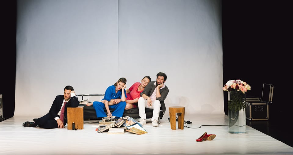 Vier Personen auf auf improvisierter Bühne, drei auf einem Sofa sitzend, eine Peson auf dem Boden