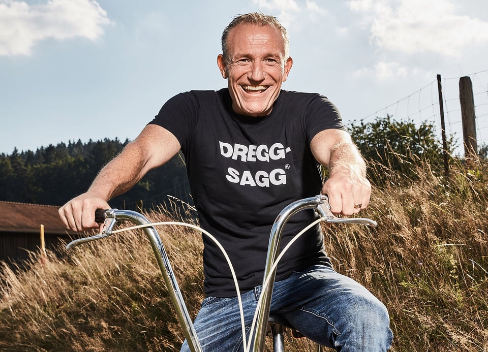 Mann in schwarzem Shirt und Jeans auf Bonanza-Fahrrad mit Landschaftshintergrund