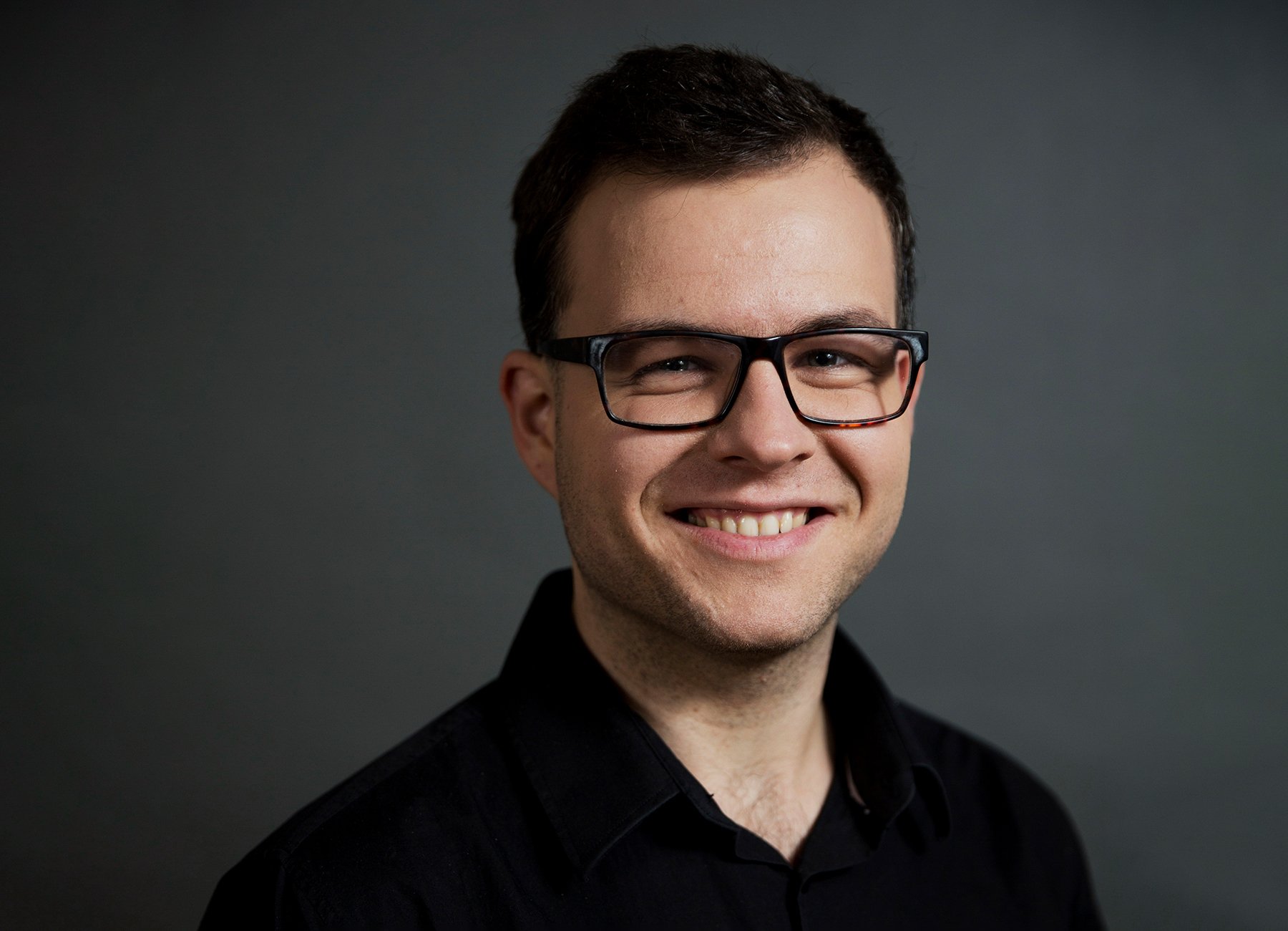 Mann mit Brille und schwarzem Hintergrund