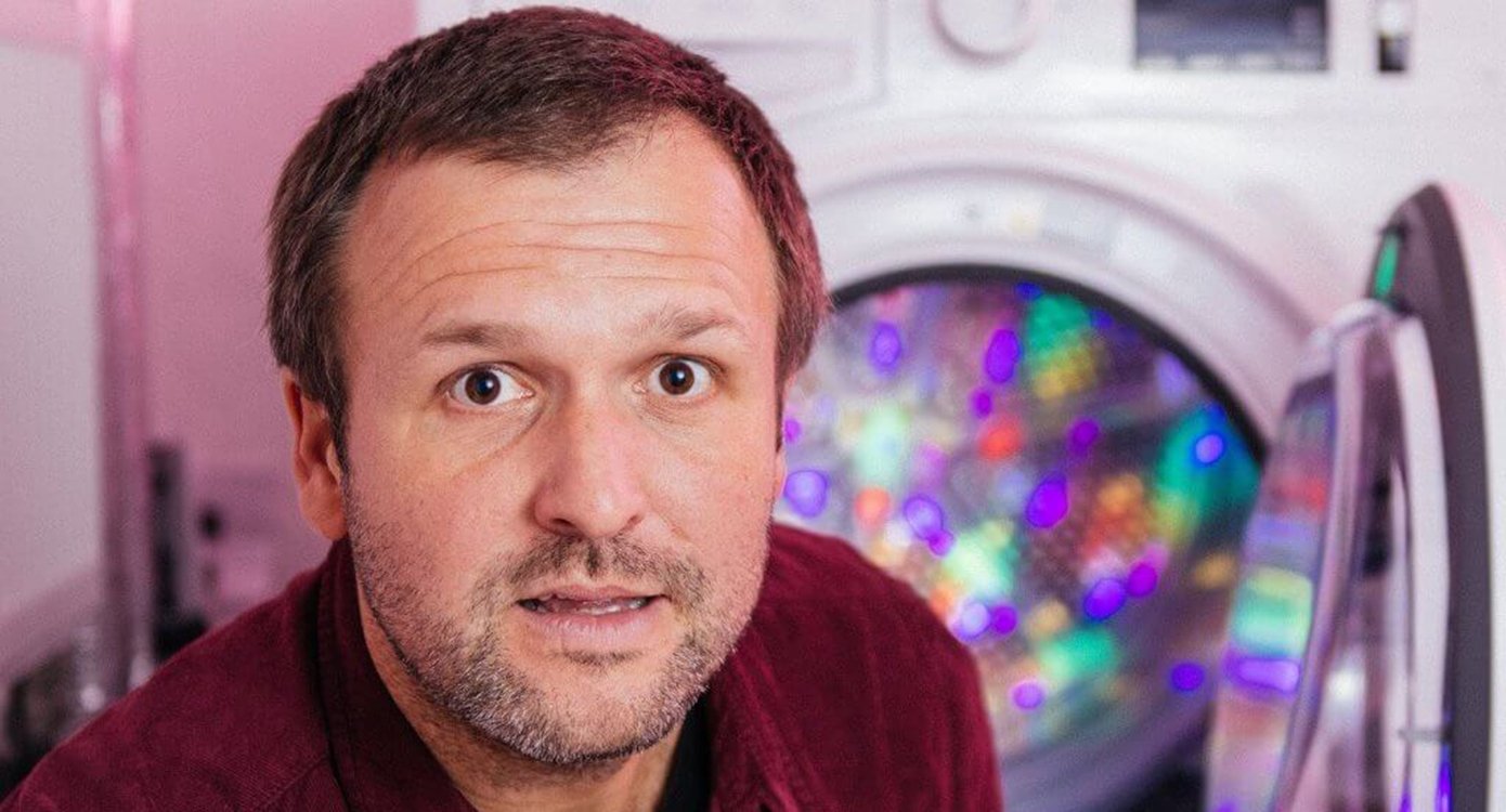 Gesicht eines Mannes mit einer Waschmaschine im Hintergrund