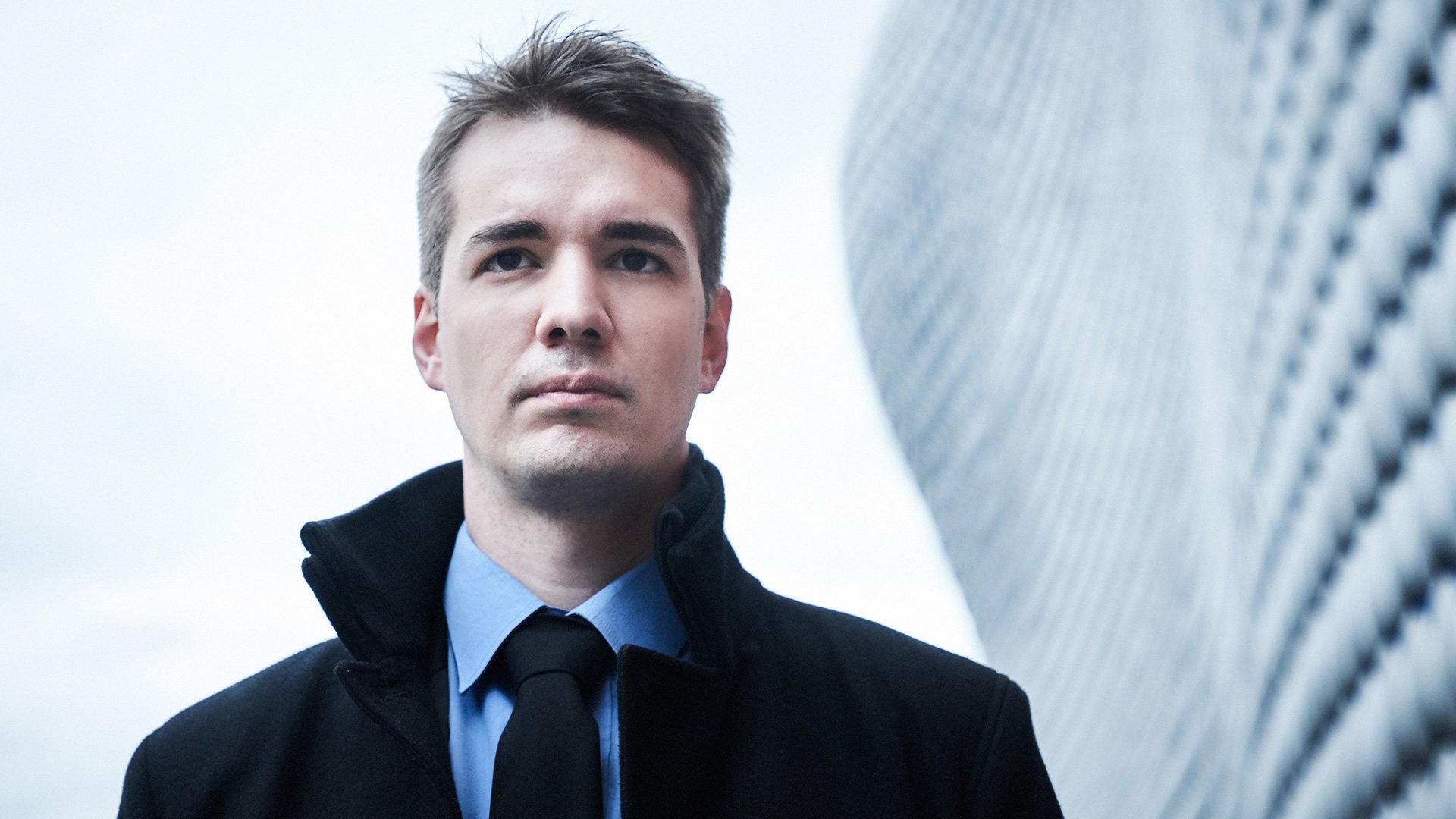 Foto für das Event von Daniel Lebhardt mit dem Gesicht des Künstlers vor einem weißen Hintergrund und einem verschwommenen Gebäude