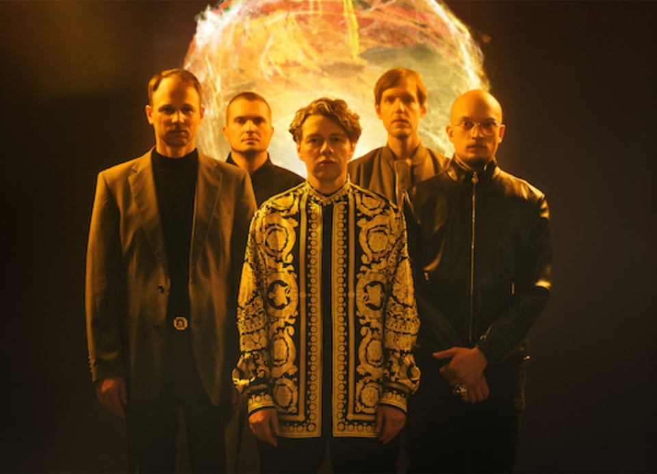 Foto der Band mit einer Art leuchtender Kugel im Hintergrund.