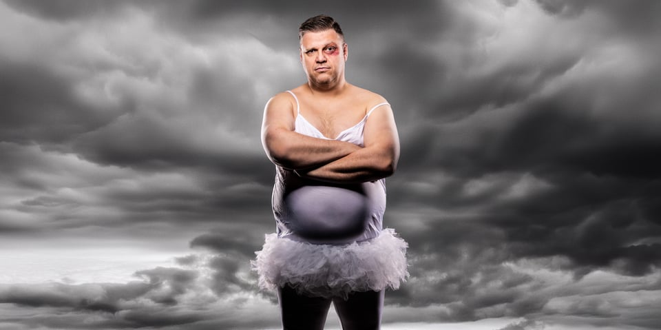 Foto von „Ralf Winkelbeiner“ im fliederfarbenen Kleid mit einem blauen Auge. Im Hintergrund graue Wolken