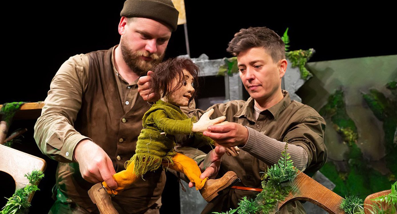 Zwei Personen mit Puppe spielend