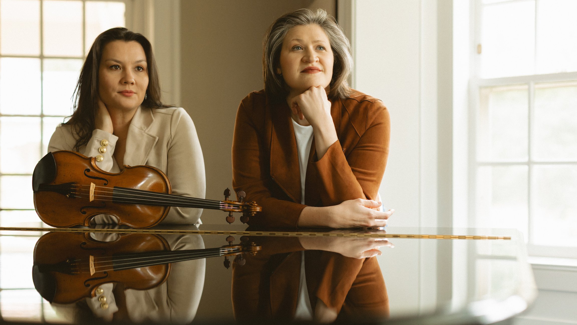 Zwei Künstlerinnen stehen an einem Konzertflügel mit einer Violine