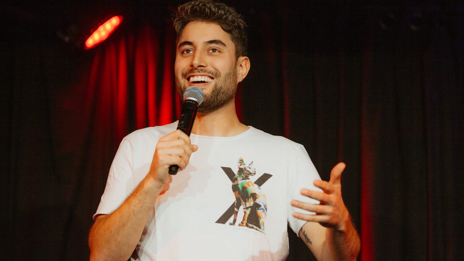 Julian Wolber auf der Bühne in weinem weißen Shirt mit Mikrofon