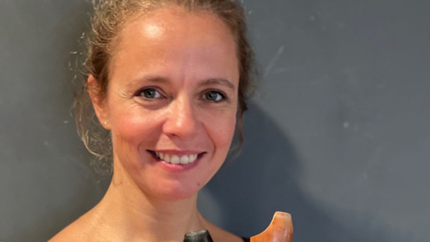 Die Künstlerin Frauke Schmitt und das Mundstück ihres Instrumentes vor grauem Hintergrund