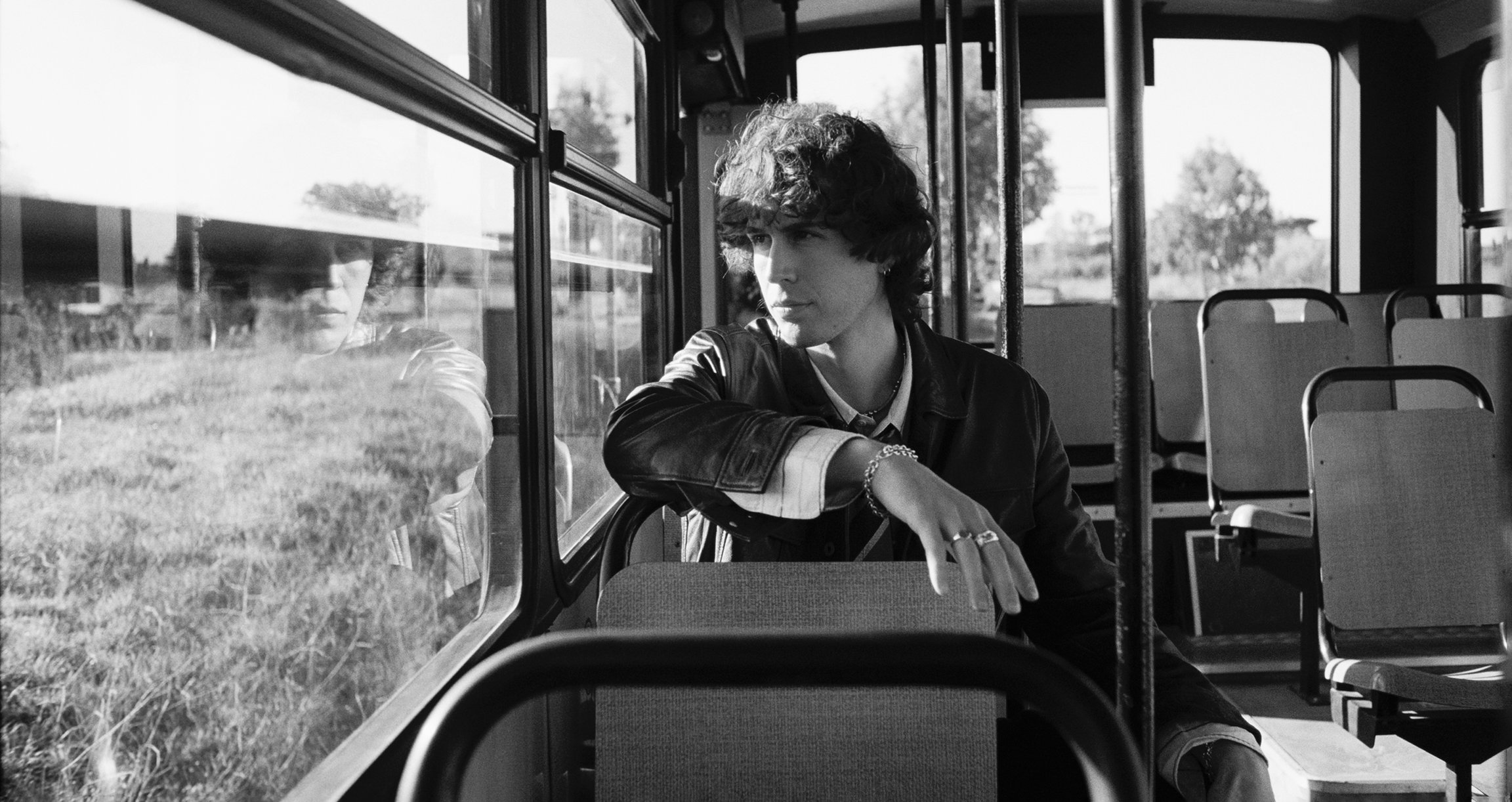  schwarz weiß Foto von einem Mann der im Bus sitzt und aus dem Fenster schaut