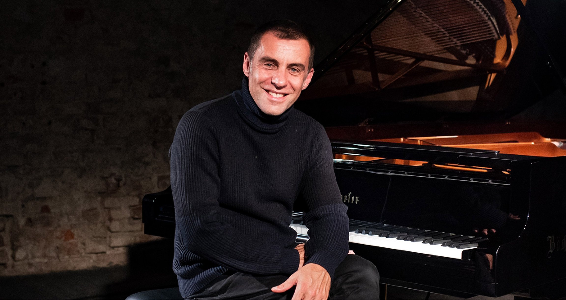 Foto des Künstlers Martin Schmitt, schwarz gekleidet, sitzend an einem Klavier.