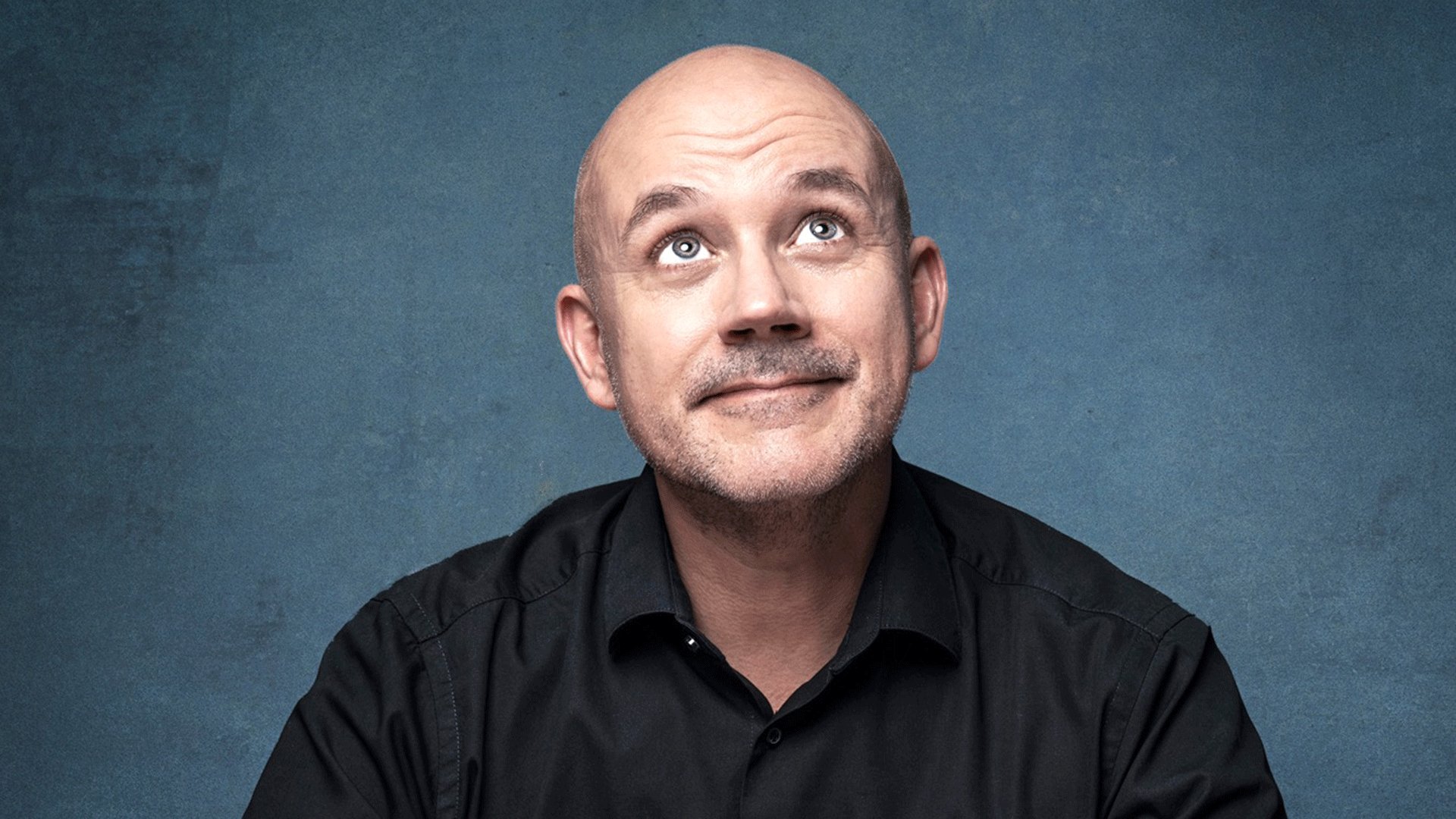 Portrait von Frank Fischer vor einem blauen Hintergrund wie er den Blick nach oben gerichtet hat