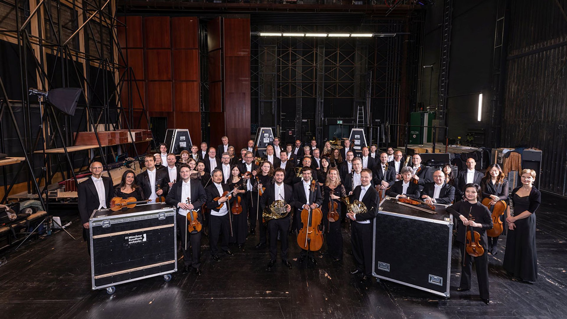 Das Orchester in schwarzer Kleidung mit Instrumenten in einer Halle