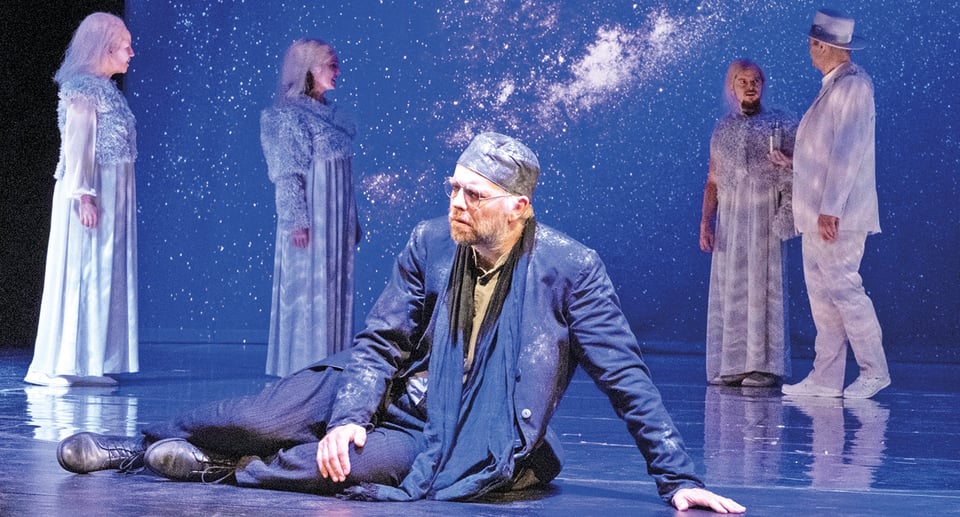 ein Foto der Bühne mit mehreren Schauspielern, von denen einer auf dem Boden liegt