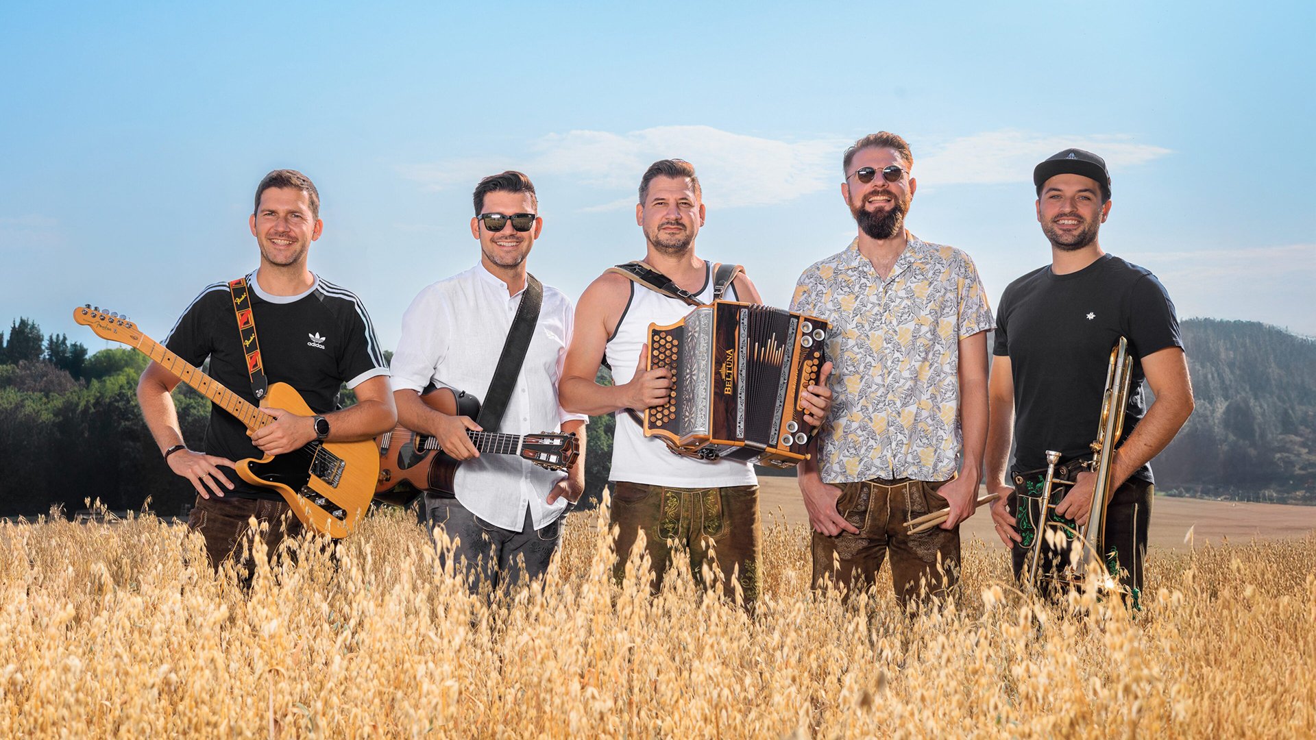 Die fünf Musiker der Band mit Instrumenten in einem Kornfeld stehend