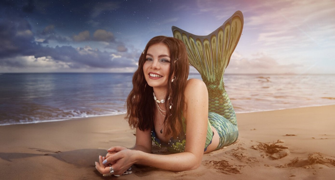 Dame mit langen braunen Haaren an Strand liegend, mit Monoflosse