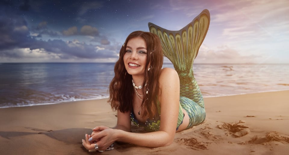 Dame mit langen braunen Haaren an Strand liegend, mit Monoflosse