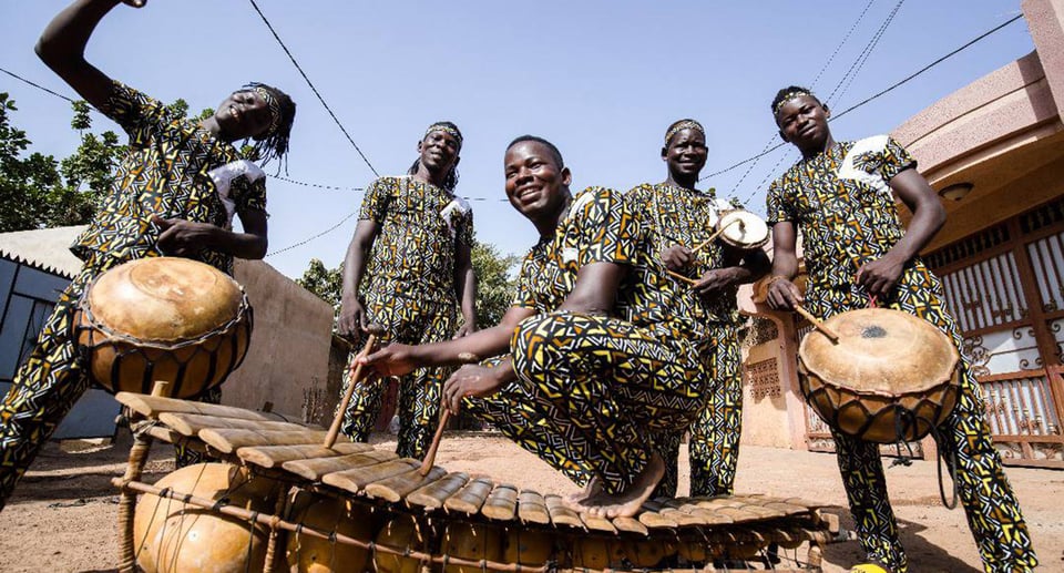 Fünf Männer mit afrikanischen Instrumenten unter freiem Himmel