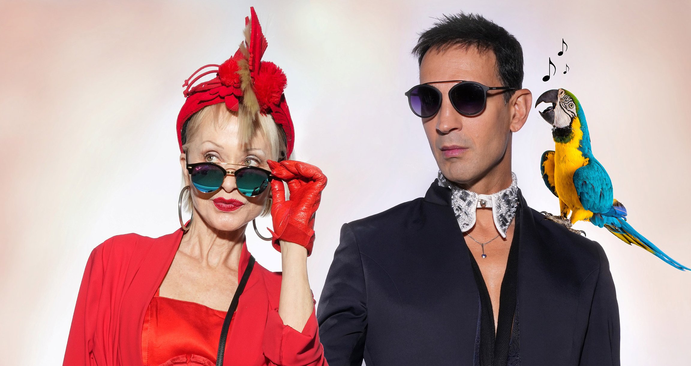 Foto für das Event „Schwarzblond: MITTERNÄCHTLICHES MONDSCHEINWUNDER“ – eine Frau in rotem Outfit mit Sonnenbrille, ein Mann ebenfalls mit Sonnenbrille und ein Papagei auf der Schulter