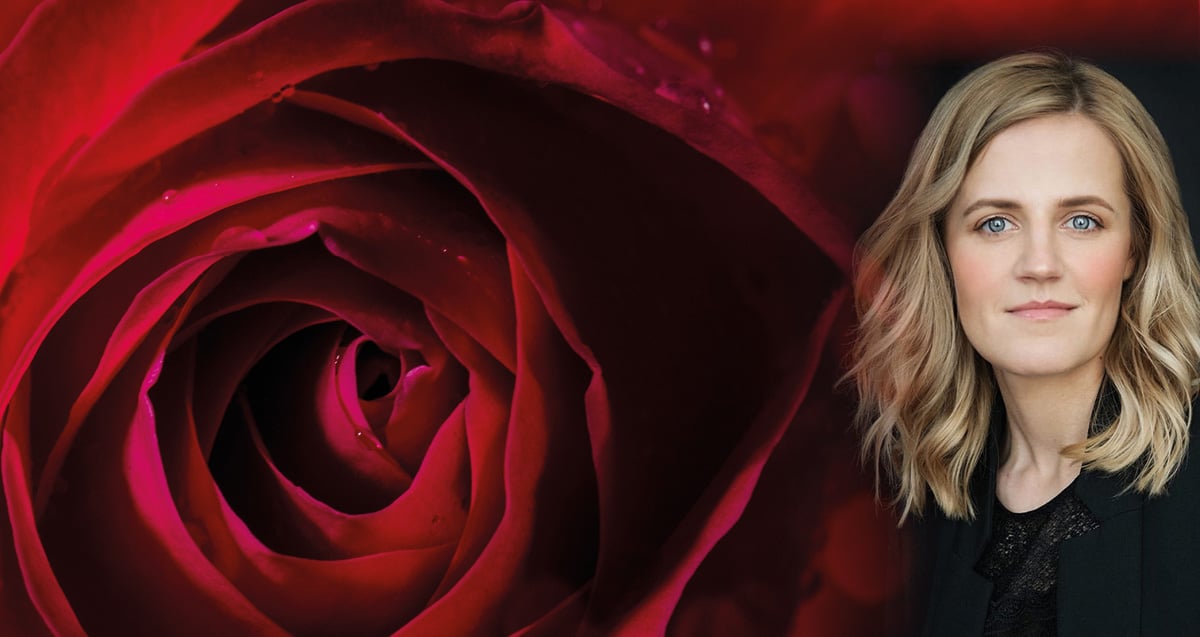 Eine Frau stehend vor einer großen roten Rose