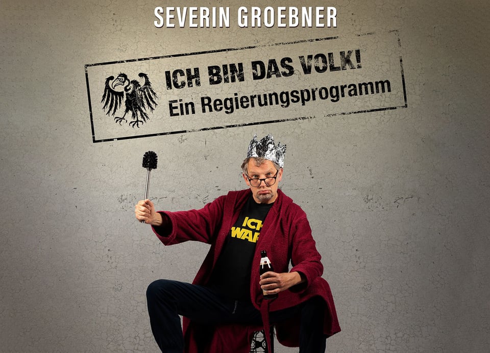 Mann mit Krone  n rotem Bademantel  und Toilettenbürste in der Hand sowie Aufschrift