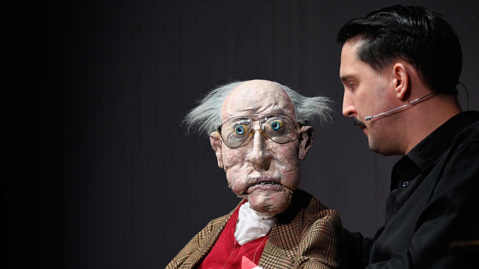 Ein Schauspieler bedient eine Bauchrednerpuppe.